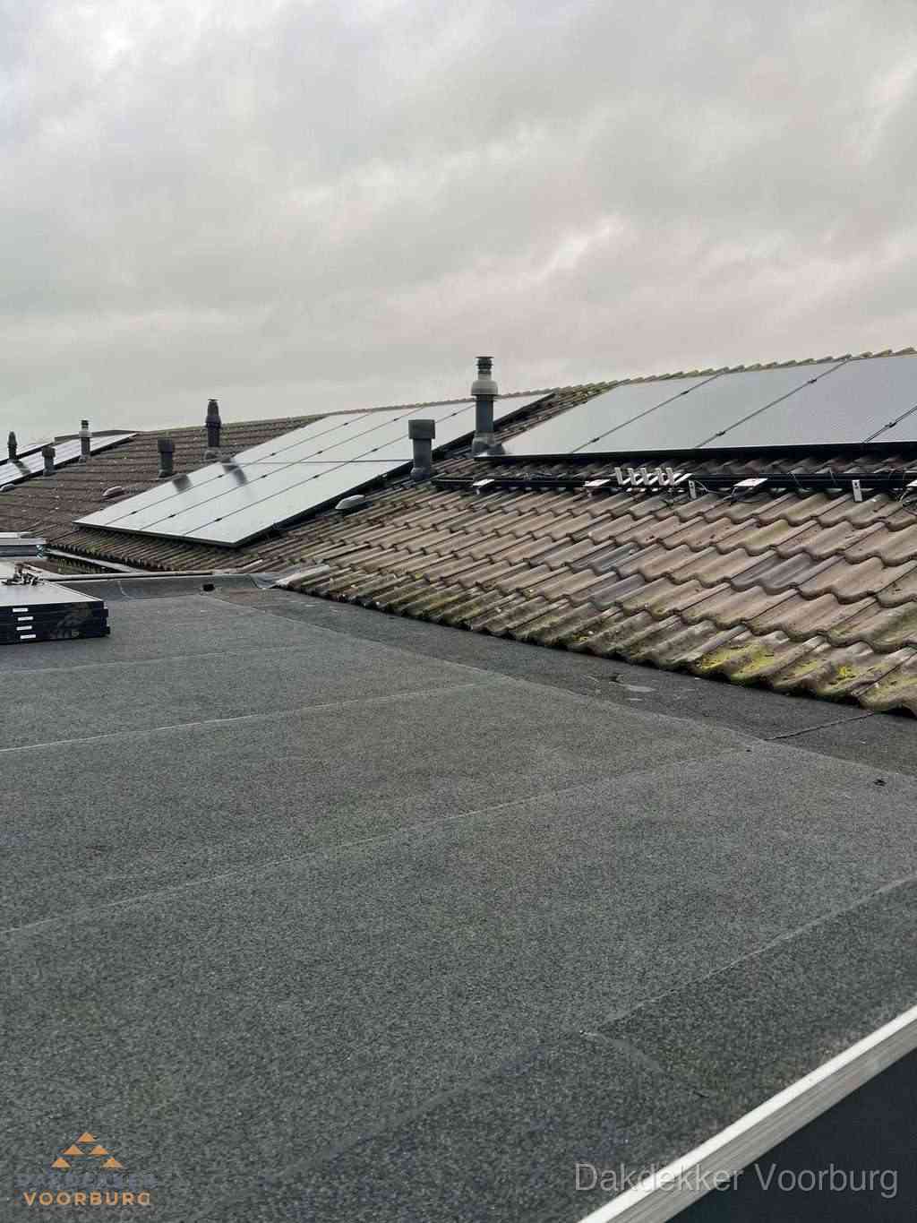 Plat dak inspectie met bitumen bedekking naast schuin pannendak in Voorburg