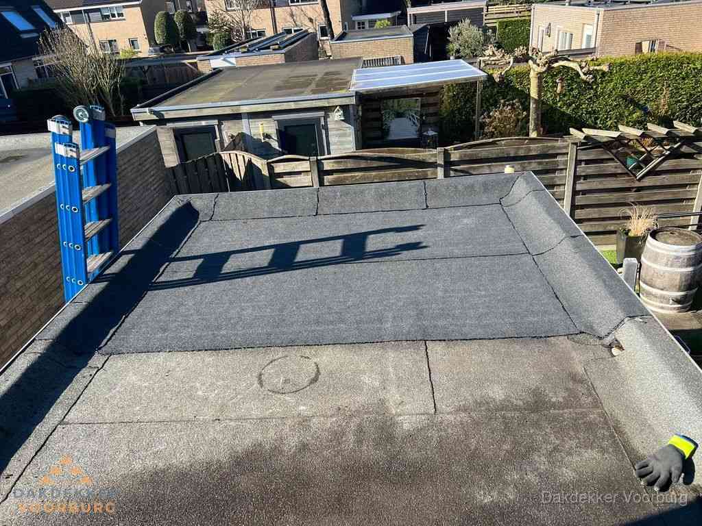 Dakdekker legt onderlaag op plat dak met houten constructie in Voorburg