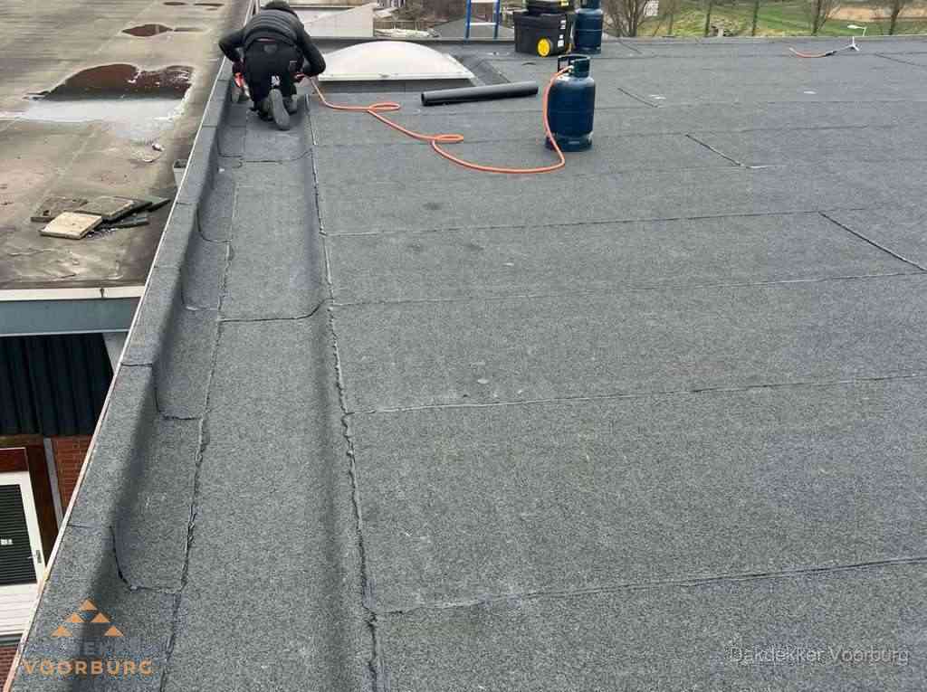 Dakdekker repareert bitumen dakbedekking op groot plat dak in Voorburg