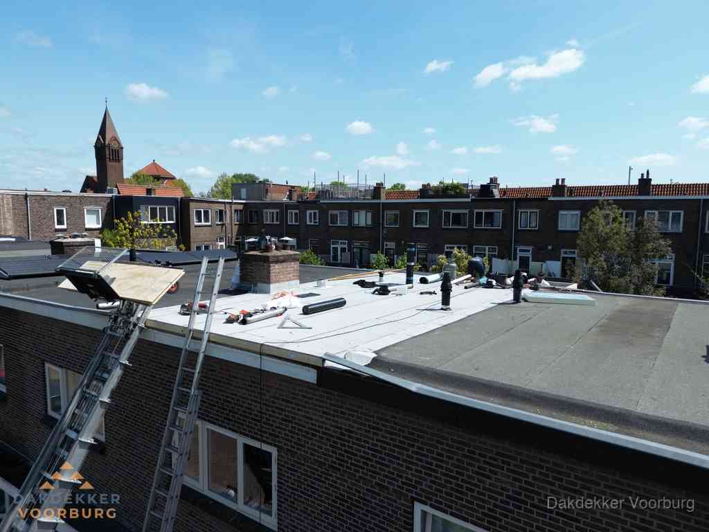 Dakdekkers aan het werk op plat dak in Voorburg