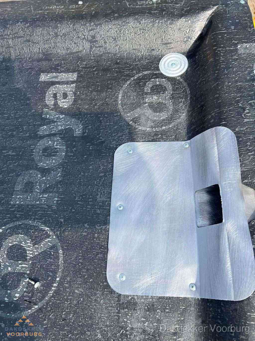 Dakdoorvoer met metalen afvoerplaat op bitumen dak in Voorburg