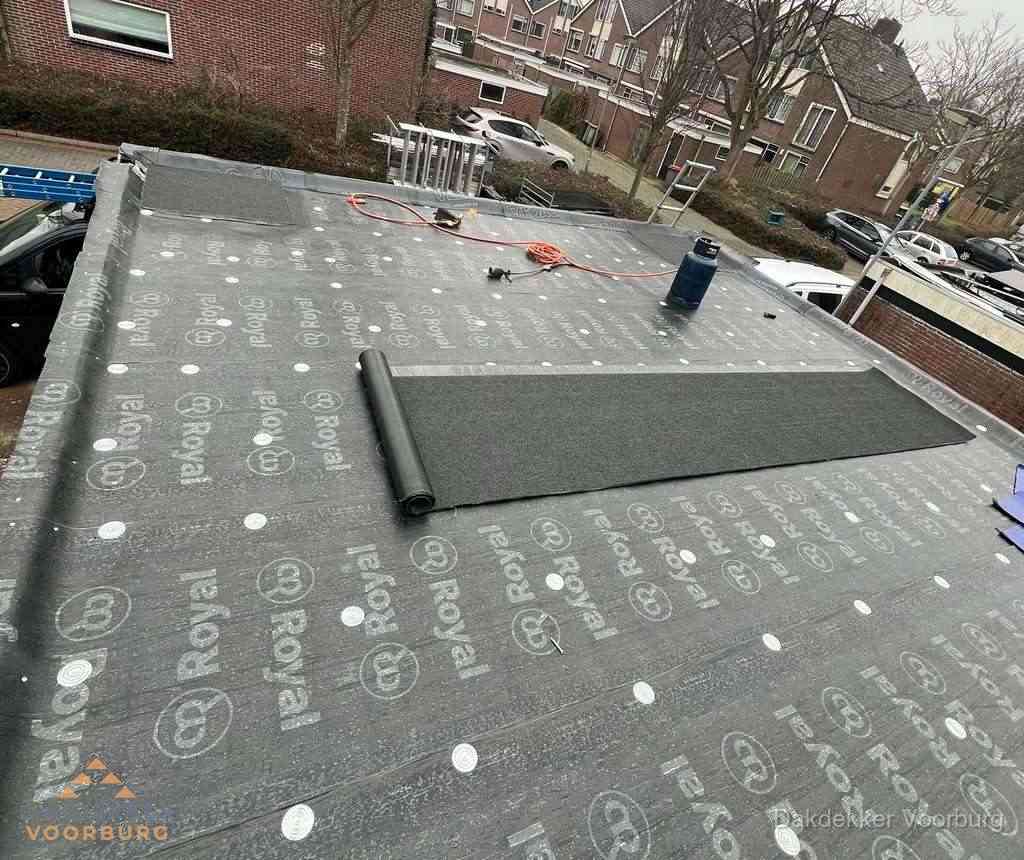 Dakdekker aan het werk met gasbrander op plat bitumen dak in Voorburg